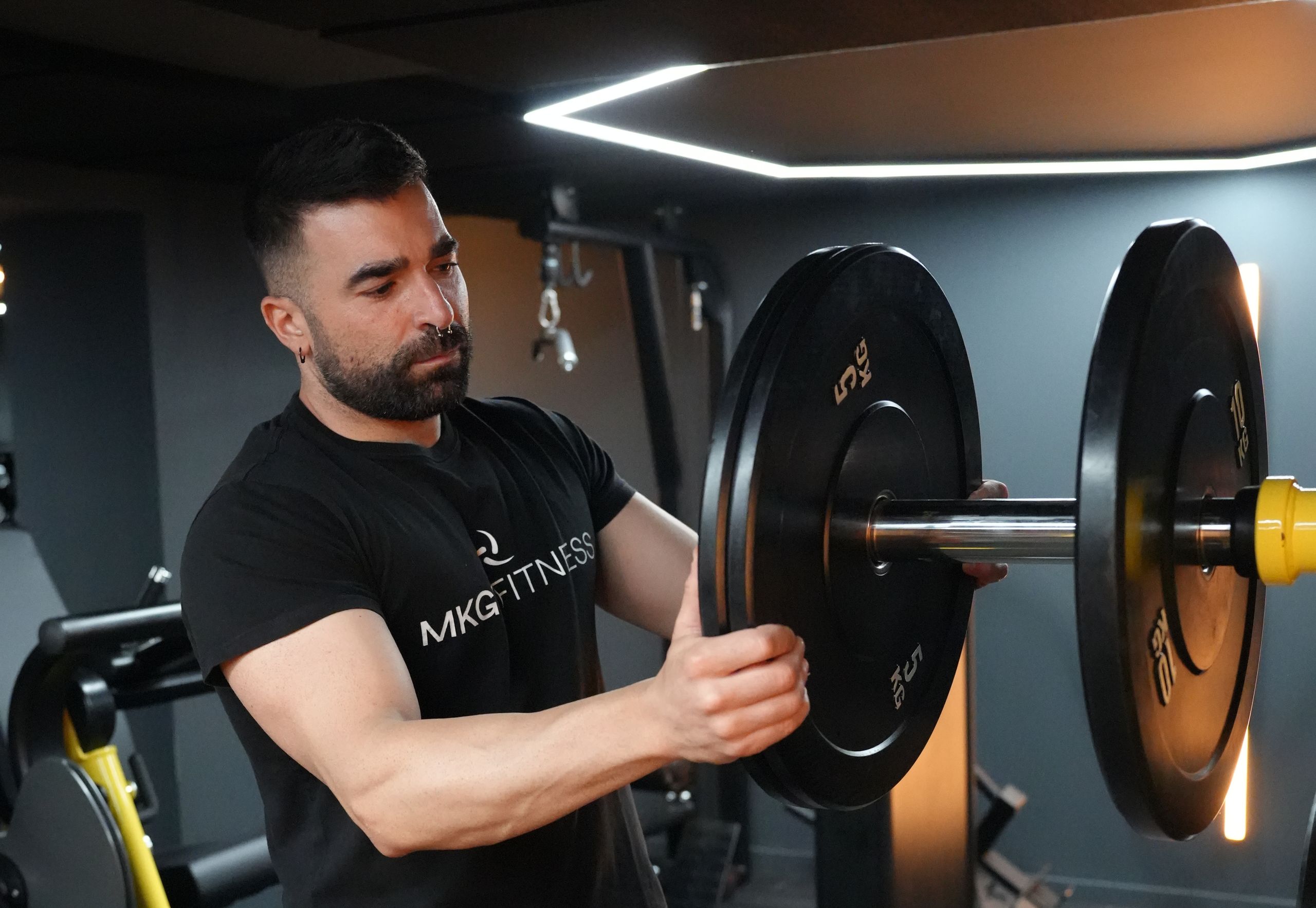 Mikel colocando discos en una barra del gimnasio MKGV